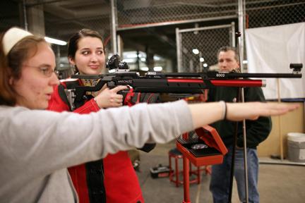 Junior in business administration Katie Siegert uses her arm to demonstrate to sports writer Kate Shefte how to properly shoulder her rifle Tuesday at the practice range in the basement of Reynolds Coliseum. "I love shooting, it's very calming," Siegert said. "You have to focus so hard." Photo by Chris Sanchez