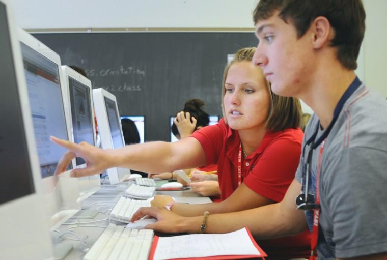 Pointing at something on the screen, Katie Nehm, second-year studying communication, helps Wade Rothrock, first-year studying pyschology, with registration for his fall classes. With the new orientation schedule, new students have holds on their accounts until the morning of the second day. &#8220;I feel like the orientation counselors and advisors help it go a lot faster,&#8221; Nehm said.