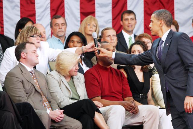 President Barack Obama hands a microphone to Patty Briguglio, owner of MMI Public Relations in Raleigh, N.C. at a town hall meeting in July. Photo by Michele Chandler