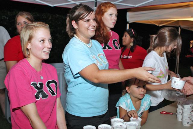 Lauren Bola, a junior in animal science, and Katie Burgess, a sophomore in psychology, give out ice cream to students attending the Panhellenic Association Ice Cream Social. "It's been an awesome turn out. It's been crazy," Burgess said. The Panhellenic Association Ice Cream Social was at Harris Field on Aug. 15. Photo by Michele Chandler