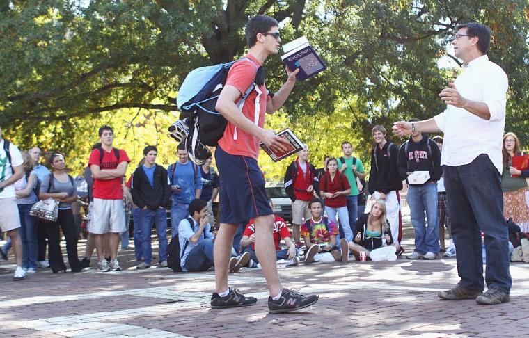 Thomas Richardson, a graduate student in operations research, engages in a debate on micro- and macroevolution with pastor Tom Short in the Brickyard. "The way he was talking, it kind of warranted someone to argue with him," Richardson said. With library books in hand, Richardson made his point to Short face to face. "It's not like I have it memorized. I'll find sources." Photo by Marisa Akers