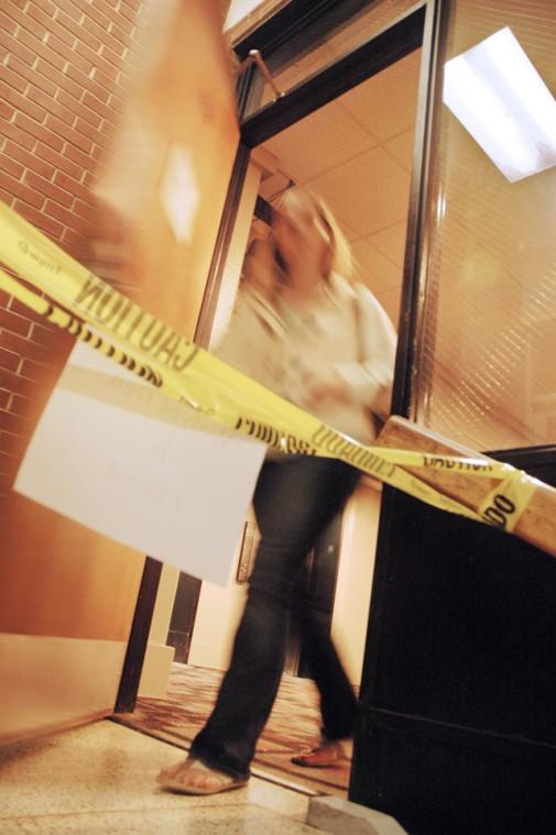 Hillary Simpson, a junior in biochemistry, walks past the caution tape blocking the staircase outside of the Wolves' Den Monday evening. The Wolves' Den, which will be closed for the remainder of the week, experienced a plumbing problem earlier this week. "I dont think it will really affect many people," Simpson said, "people are headed out for Thanksgiving, and it will be open by the time they get back." Photo by Jordan Moore