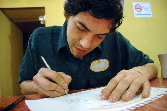 McBryde Cameron, a junior in creative writing, works on a Valentine&#8217;s Day card for his girlfriend at Cup A Joe. &#8220;I could buy her a card, but it would be more fun and more personal for me to make it, so that&#8217;s what I&#8217;m going to do,&#8221; Cameron said. The coffee shop is a hot spot for many students because of its retro feel, eclectic crowd and always-available coffee. Photo by Christin Hardy
