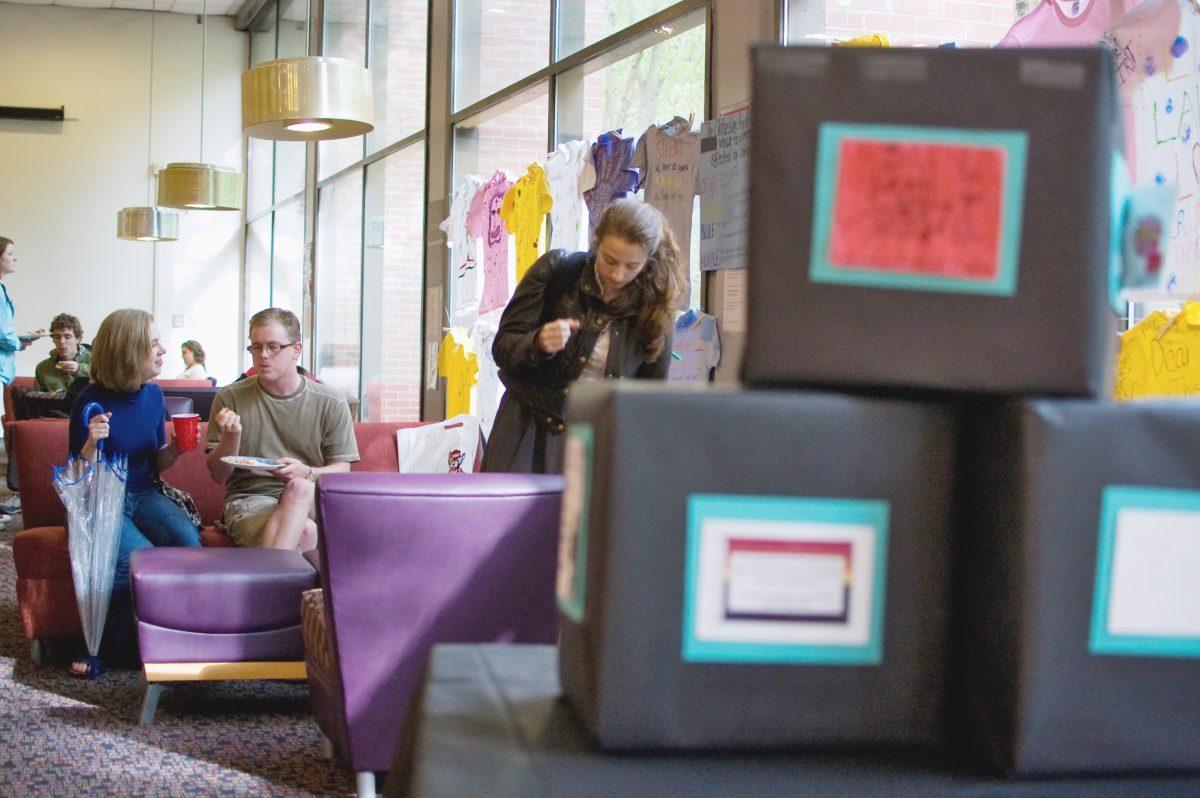 Alison Sappie, a senior in pre-vet, and Brendan McLaughlin, a senior in communication, eat and drink refreshments after browsing the displays in the PostSecret event held in Caldwell Hall on Wednesday. Meanwhile, Katrina Jiamachello, a sophomore in zoology and this year's vice president of "The Movement" to end interpersonal violence, helps finish setting up for the event. Photo by Amanda Karst