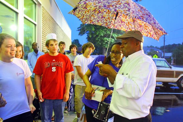 Erik Fessler, sophomore in FYC, waits for Ayana Hernandez, Public Relations for Krispy Kreme as well as a coordinator of the opening event, and Michael Dillon, a manager, to announce the customer selected to turn on the &#8220;Hot Now&#8221; sign, which signaled the official reopening of the Peace Street Krispy Kreme store.