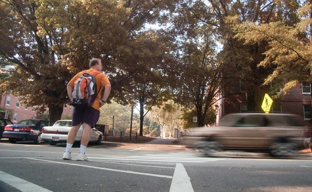 A pedestrian waits for the cars driving along Cates Avenue to pass before crossing via the crosswalk between Carmichael Gym and central campus. Though the cars did not stop for him at the crosswalk, most pedestrians Wednesday afternoon were able to cross the street without delay.
