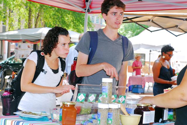 Marc Mueller, a senior in environmental engineering, and Marie Douglas Hamm, in lifelong education, sample the products from Yah's Best Salsa at the Campus Farmer's Market in the Brickyard on Wednesday. Yah's Salsa is made completely by hand by the owner Paige. "I really like the how there are so many flavors and they are all so fresh," Hamm said.