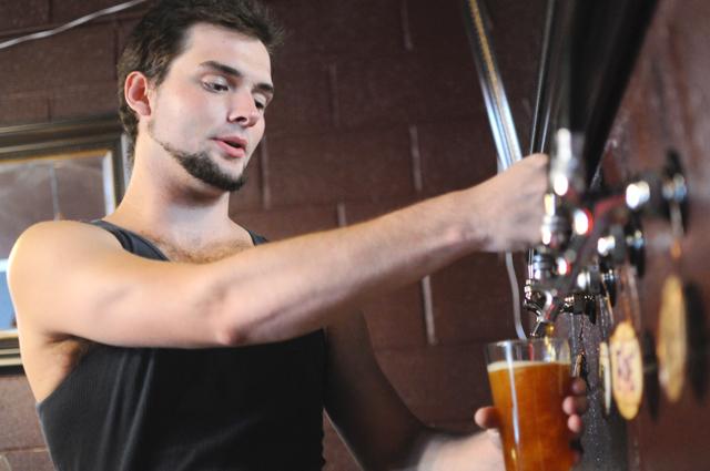 In the Roth Brewery Tap room, Eric Roth, a senior in agricultural business management, pours one of his pale ales that his brewery made. Roth created a brewery from scratch with his brother Ryan. Photo by Luis Zapata