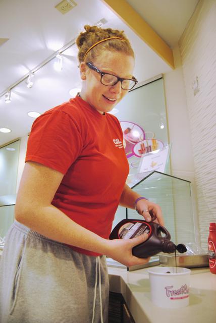 At the new FreshBerry location on Hillsborough Street, Julia Belcher, a freshman in nutrition, adds chocolate syrup as a final touch to her frozen yogurt. &#8220;I like FreshBerry because I love frozen yogurt and they have a wide selection of yogurt flavors and toppings,&#8221; Belcher said. FreshBerry offers a total of eight frozen yogurt flavors and 48 possible toppings to select from. Photo by Hannah Jaffee