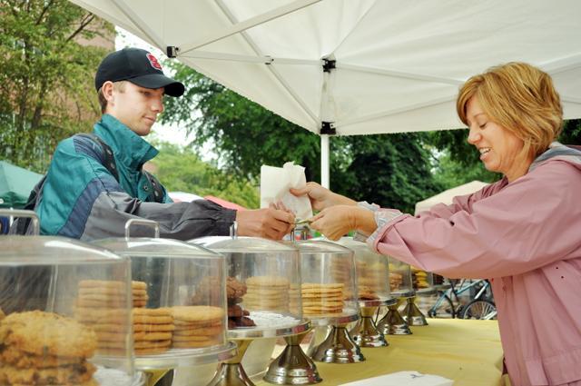 First Year College freshman Michael Simon pays for his cookies at the Sept 29 farmer's market. "I usually come here every wednesday and get cookies," Simon said. "My favorite is the triple chocolate." Photo by Alex Sanchez.