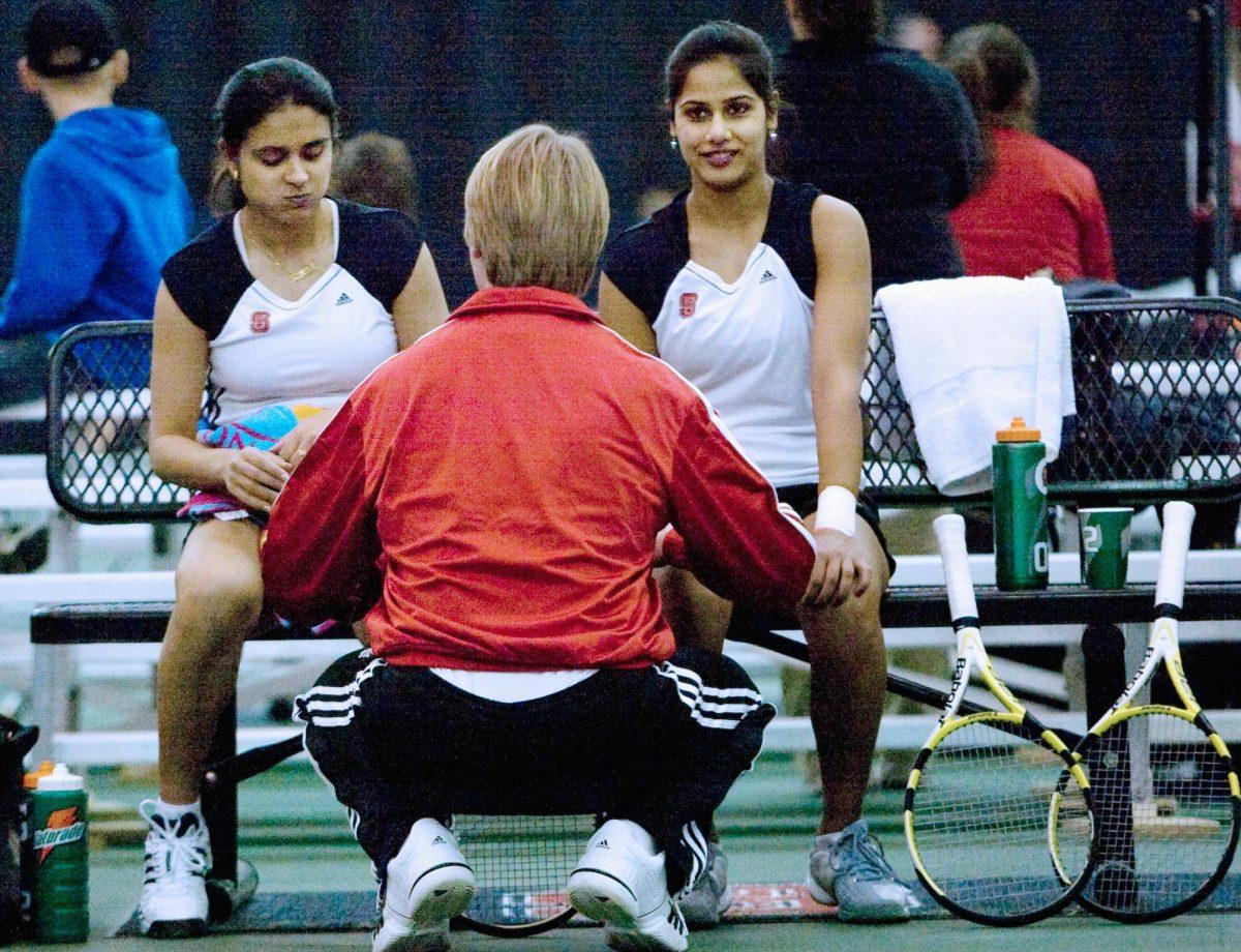 Coach Hans Olsen talks to Sanaa Bhambri and Sandhya Nagaraj after winning their doubles match against Charleston Southern University.