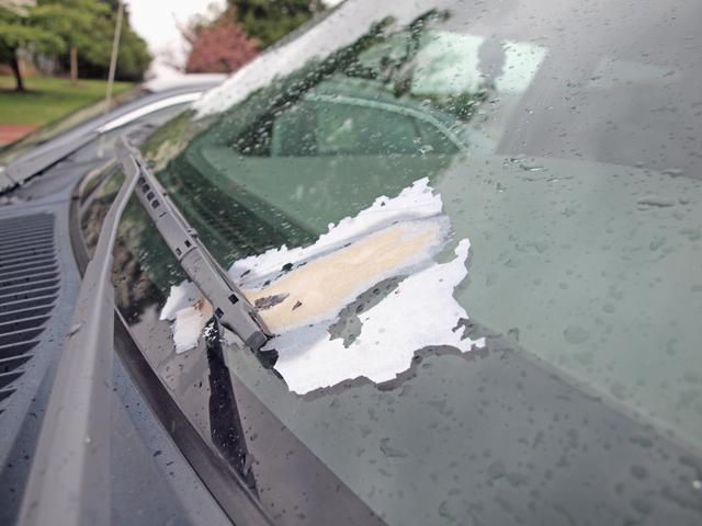 Damage from an advertisement left on a car's windshield in an RW-Zone parking lot. Damage like this is fairly common in parking lots near dormitories. Many advertisers, like the Fubar night club in Raliegh, print their advertisements on paper that leaves hard-to-remove residue if exposed to heat and rain. Photo by Aaron Andersen.
