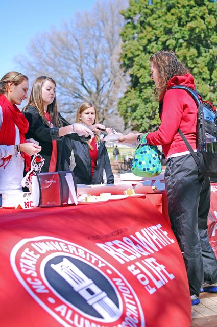 Amanda Young, a sophmore in management and Natelie Hawley, a senior in elementary education distribute free cake in the brickyard to celebrate NC Sate's 124th birthday. The Alumni Association celebrated founders day not only to remember State's birthday but to recruit new members enthusiastic about NCSU. Group member Caroline Linker, a junior in Communication and Public Relations said, "We have had a great turn out this year; it could be one of our biggest recrutments yet".Photo by