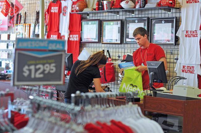 Derrick Brown, a senior in statistics and economics, bags a thermodynamics book for a customer at Packbackers Tuesday, July 5. Brown works full time at the local store during summer, but has to work less during the fall and spring semesters. Photo by Jordan Moore