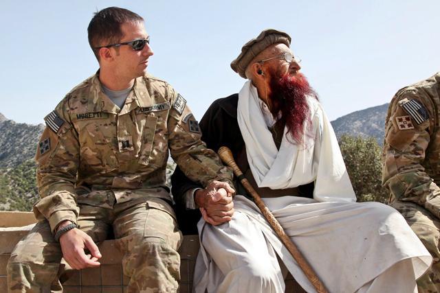 KUNAR PROVINCE, Afghanistan &#8211; U.S. Army Capt. Mark Moretti, commander of Company B, 2nd Battalion, 12th Infantry Regiment, Task Force Lethal Warrior, sits hand-in-hand with Shamshir Khan, one of the most senior Korengal Valley elders, April 13, at the Korengal Outpost in Kunar province, Afghanistan. Photo courtesy of the Defense Department.