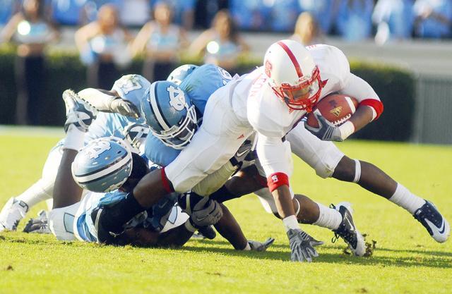 On the blades of Kenan Stadium, sophomore halfback James Washington is tackled by three UNC defensivemen Saturday, Nov. 20, 2010. Washington had 45 rushing yards. N.C. State beat UNC 29 - 25. Photo by Luis Zapata