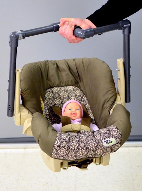 Michael Clamman, a doctoral student in industrial engineering, holds an infant car seat with a newly designed handle in his right hand. By changing the angle of the handlebar, it makes it easier to carry the infant car seat. Photo by Paul-Gregor Maier