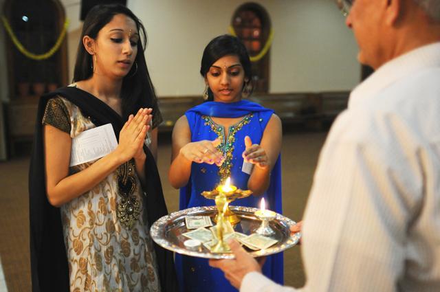 Ripsi Patel, a junior in psychology, and Khevna Desai, a sophomore in political science, bathe in the candle light of their offering during their visit to temple. Patel and Desai practice hinduism, a monotheistic religion celebrating many forms of the supreme being "Brahman." Hinduism is an ancient religion, practiced throughout India and Asia, and can be traced back nearly 7,000 years. photo by Jordan Moore