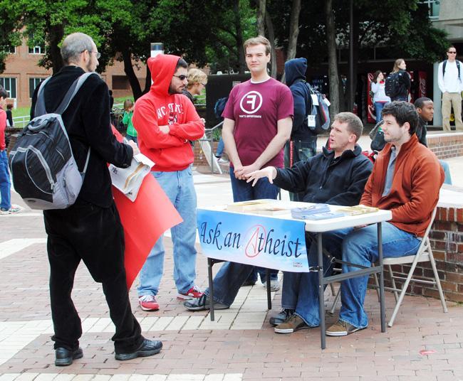 Members of the Secular Student Alliance field questions about atheism from a brickyard preacher. "Atheists are like snowflakes, no two are the same. You find very few that reach a conclusion to the 'God Question' the same way," said Brandon Moore, 1st year graduate student in Biomanufacturing and Engineering. "We are just a group of people who lack a belief in God or gods, but we have different beliefs outside of that." Photo by Natalie Claunch