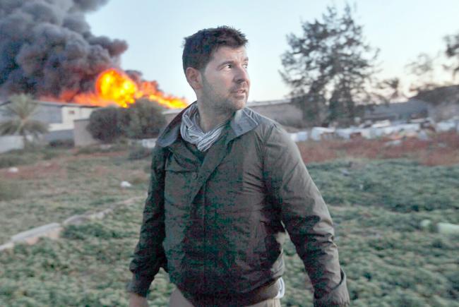 N.C. State alum and Getty Images photographer Chris Hondros stands in front of a burning building while on assignment on April 18, 2011, in Misrata, Libya. Hondros, who was on assignment in Misrata, Libya, was killed on April 20, 2011 by a rocket-propelled grenade. Photo by Katie Orlinsky via Getty Images