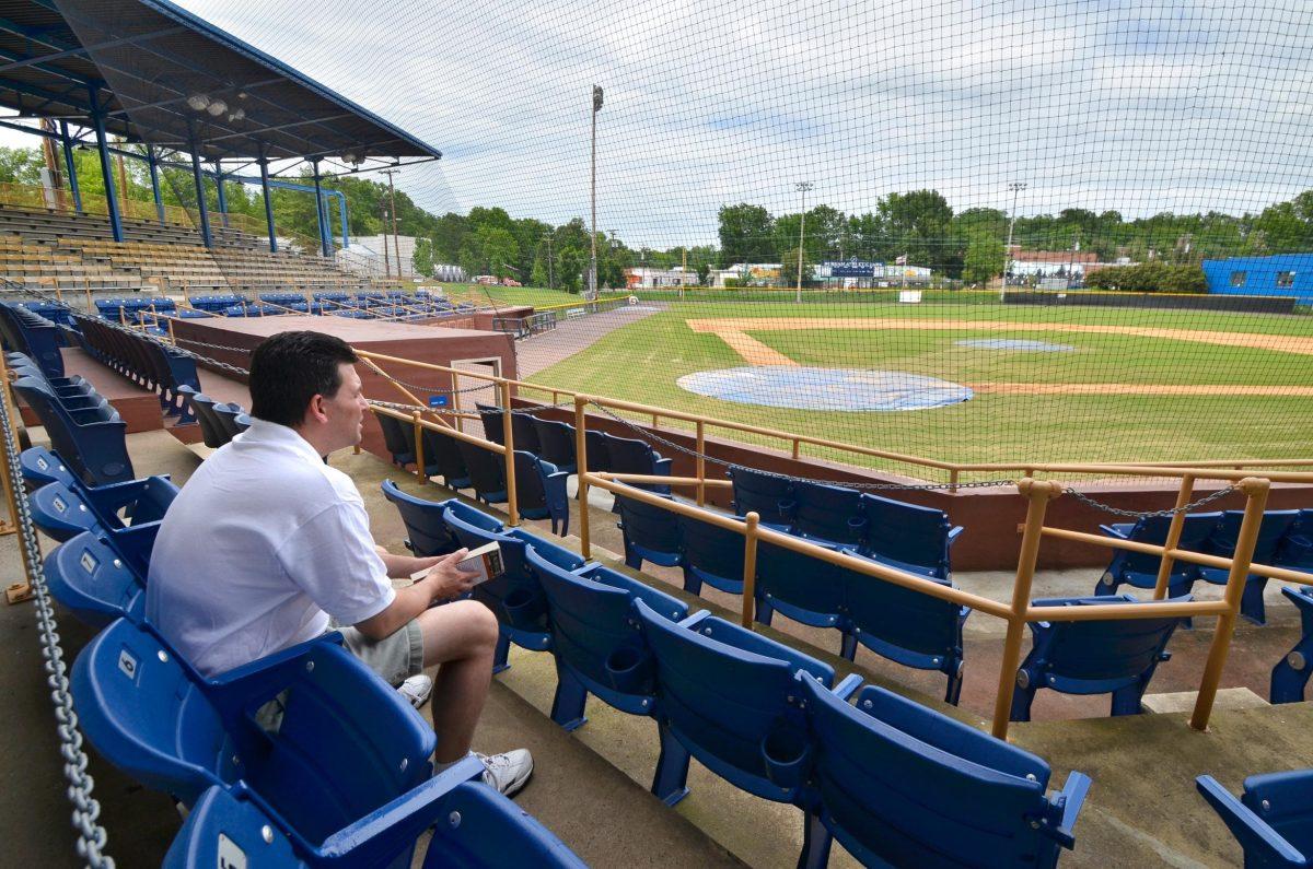 James Bailey, sports writer, sits in the Durham Athletic Park with his new book, "The Greatest Show on Dirt." Bailey worked for the Durham Bulls while studying at N.C. State. Photo by Charlie Harless