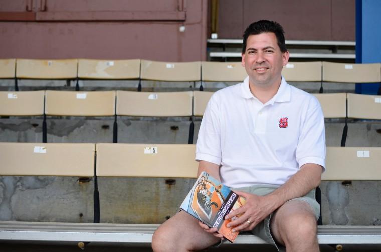 James Bailey, alum of 1993, sits in the Durham Athletic Park with his new book, "The Greatest Show on Dirt," a novel about the Durham Bulls. Photo by Charlie Harless