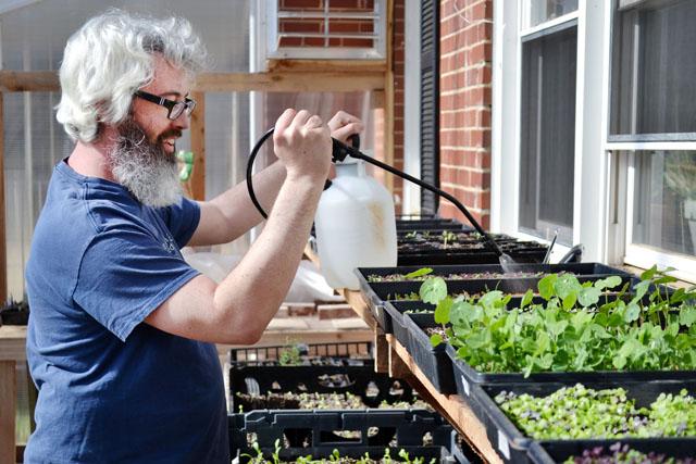 Garden manager Jason Johnson waters plants in the greenhouse. Photo by Caide Wooten.