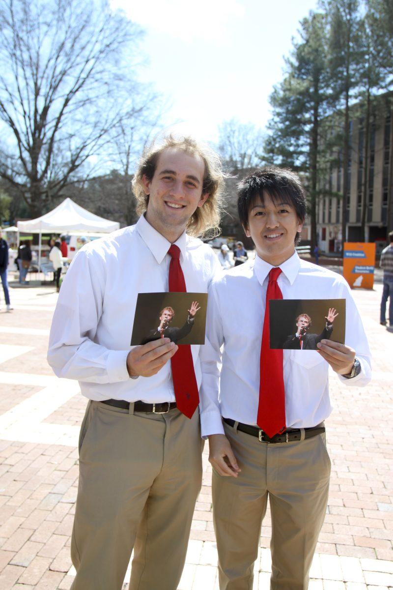Photo by Joannah Irvin. Brennen Clark, a junior in math education, and Ken Akiyama, a junior in business, hold photos in memory of Ian Peterson on the Brickyard Wednesday March 13, 2013. Students gathered together to support friends and family of Ian Peterson. "We were in Grains of Time with him," Clark said, "I learned so much from him about singing and music just from hanging out from him".