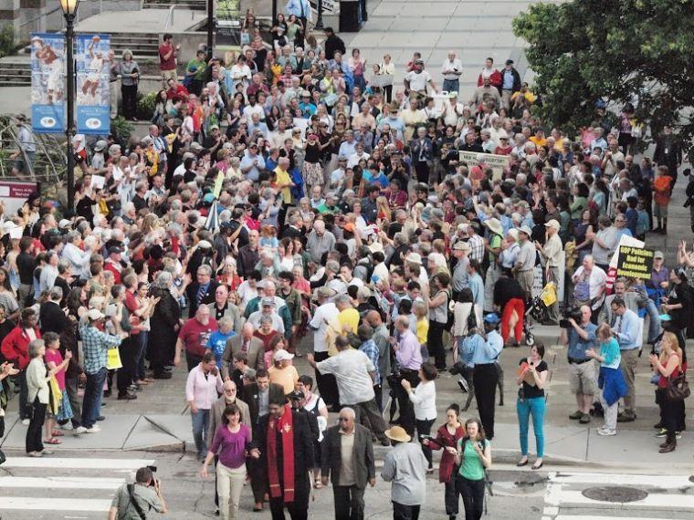 Photo credit to Vidya Sankar. Photo 1: people rallying before the civil disobedience outside the legislative building, walking toward the legislative building, led by Rev. Barber.