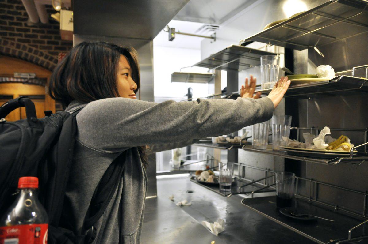 Freshman computer science engineer Caroline Law slides dirty dishes on Fountain Dinning Hall's new tray disposal system on Saturday, September 14, 2013. The new system has dramtically expedited the cleaning time for the kitichen staff. Photo by Joseph Phillips