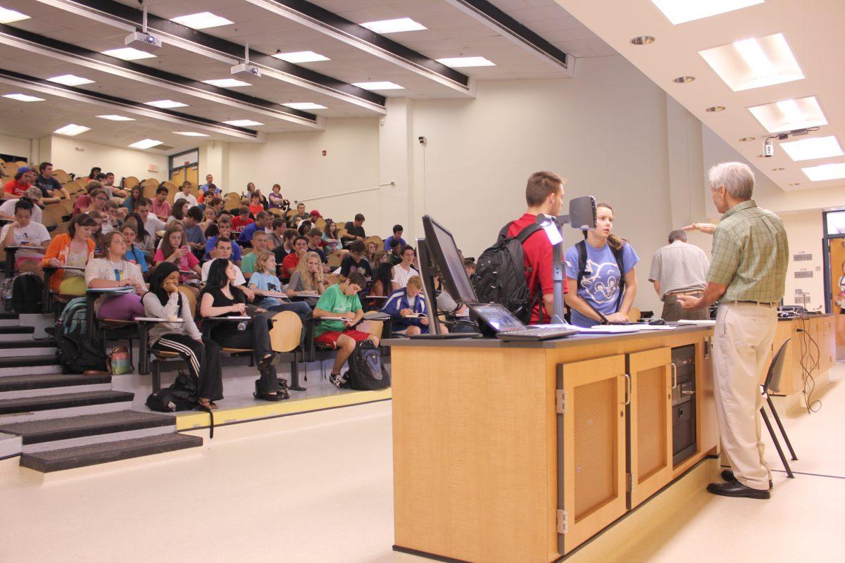 Dr. Edmond Bowden explains a chemistry topic to students after his lecture while Dr. Philip Brown sets up for his lecture in Dabney Hall on Tuesday, September 3, 2013. With the size of the CH 101 General Chemistry classes, it can be difficult for professors to have a small group discussion with students facing issues with the material.
