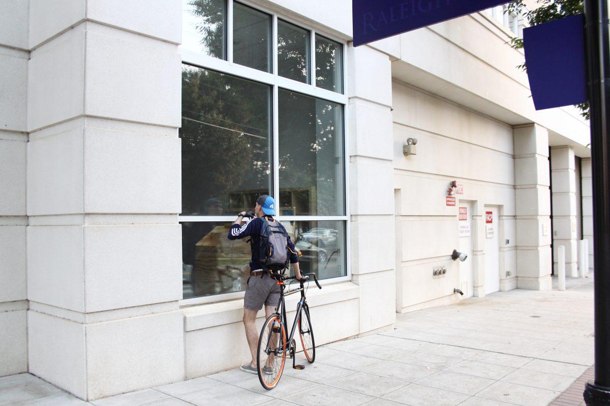 A cyclist glances from outside at construction inside Sorry State&#8217;s to-be record store at 317-105 W. Morgan St. in downtown Raleigh. Sorry State owner Daniel Lupton said its record store and new headquarters will function from the Raleigh location beginning this month.