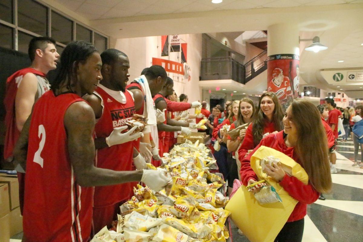 Anthony Barber, a freshman guard, and the rest of the basketball team hand out food during the 2013 Campout at PNC Arena. The 2013-2014 Men's Basketball team had a scrimmage and pep rally earlier in the evening to introduce the Wolfpack to the team.