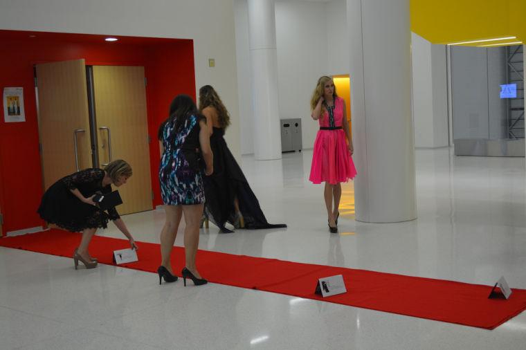 taylor quinn/Technician
Volunteers set up placards on a red carpet. The placards each display a dress designed by LeBlanc and a description of that dress.