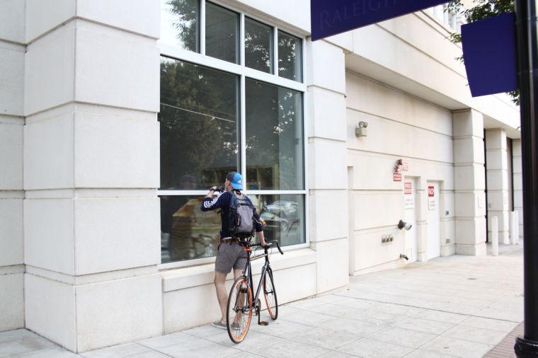 A cyclist glances from outside at construction inside Sorry State&#8217;s to-be record store at 317-105 W. Morgan St. in downtown Raleigh. Sorry State owner Daniel Lupton said its record store and new headquarters will function from the Raleigh location beginning this month.