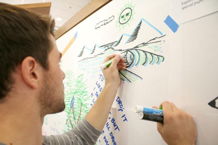 Oliver Walsh, a freshman intending to go into engineering, draws a picture of a surfer on the graffiti wall in Caldwell Lounge Monday. N.C. Sate supported the National Day of Writing by hosting this event.