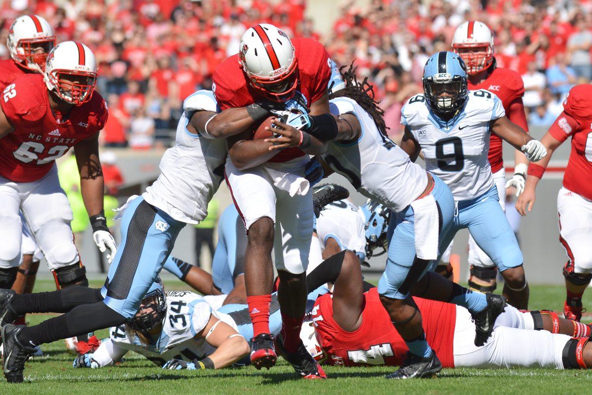 Graduate student quarterback Brandon Mitchell is tackled during the homecoming football game against North Carolina in Carter-Finley Stadium Saturday, Nov. 2, 2013. The Tar Heels defeated the Wolfpack 27-19, dropping N.C. State to 0-5 in conference play. Photo by John Joyner.