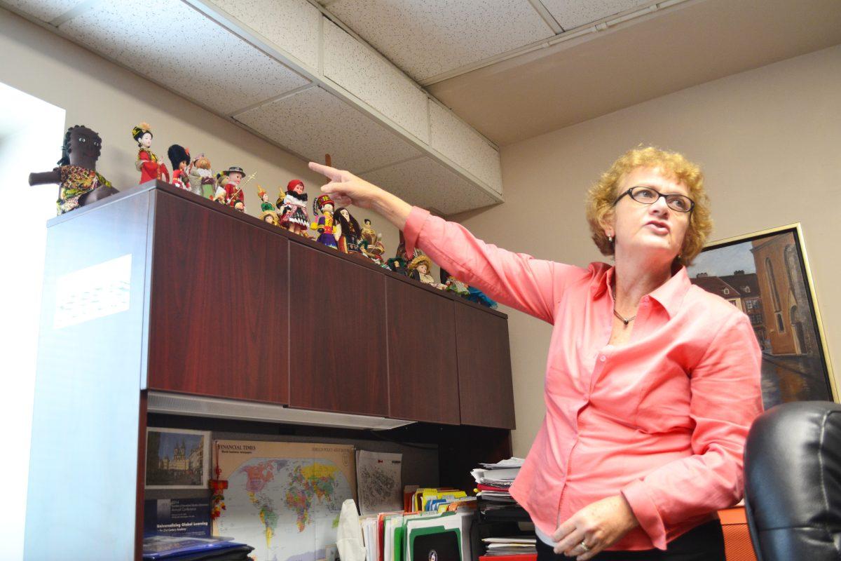 Heidi Hobbs, associate professor of public and international affairs, gestures toward her collection of dolls. She accumulated dolls through her travels and gifts from students.
