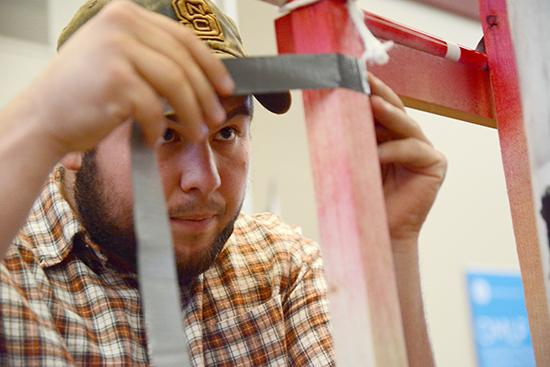 Freshman in civil engineering Ben Pierce reinforces his groups precision launcher with duct tape before preparing to present it to the judges. Pierce&#8217;s group won first place with a bulls eye at the Freshman Engineering Design Day in the McKimmon Center Tuesday.
