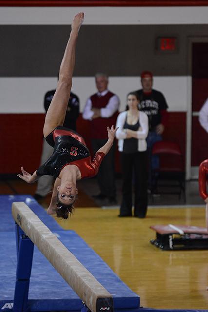 Sophomore Aubrey Hine flips on the balance beam. NC State won with a team score of 194.05 for the Beauty &amp; the Beast meet in Reynolds Colisium Friday, Jan. 24, 2014.