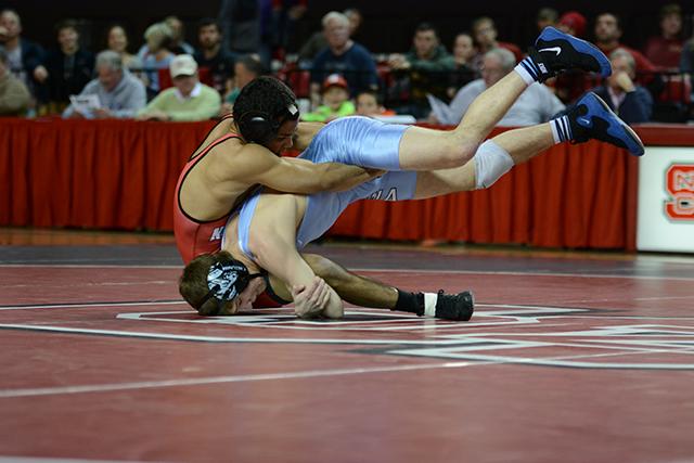 Freshman Chris Wilkes pulls UNC Troy Heilmann to the ground. Wilkes scored the decisive points with the upset over Heilmann to help the Wolf Pack beat Chapel Hill 19-16 in the ACC show down Friday, Jan. 31, 2014 in Reynolds Coliseum. Photo by Joseph Phillips