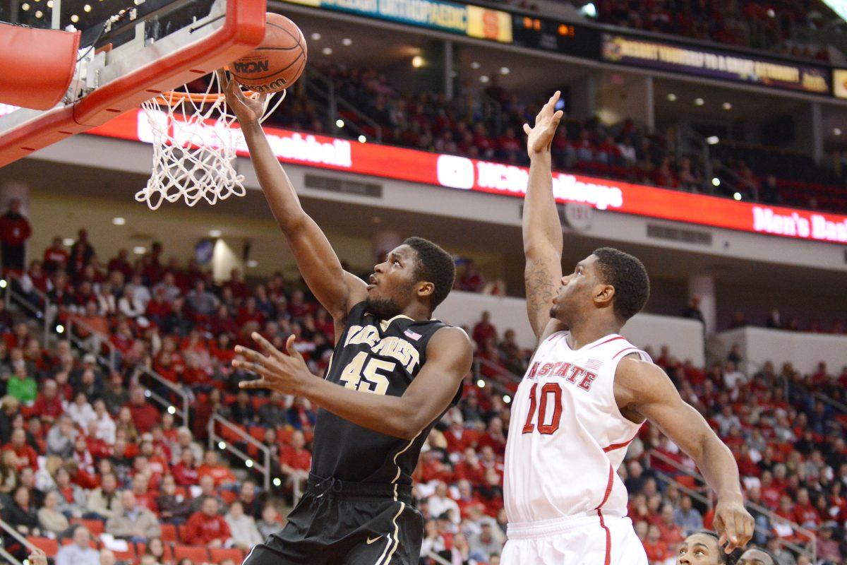 Wake Forest sophomore forward Arnaud William Adala Moto makes a layup against freshman forward Lennard Freeman during the game against Wake Forest in the PNC Arena Feb. 11, 2014. The Wolfpack defeated the Demon Deacons, 82-67.&#160;