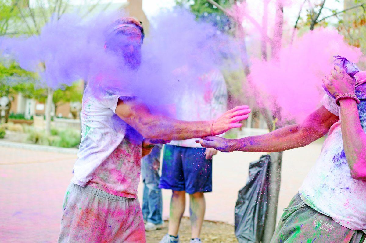 Ashton Lewis, former junior in agriculture business, and Bradon Niles, former junior in German and international studies, duel off and throw paint at each other during the annual Holi celebration at Wolf Plaza. Lewis heard about the event from his roommate and dueling partner, Niles. Lewis said that his favorite part was just coloring other people. ARCHIVE
