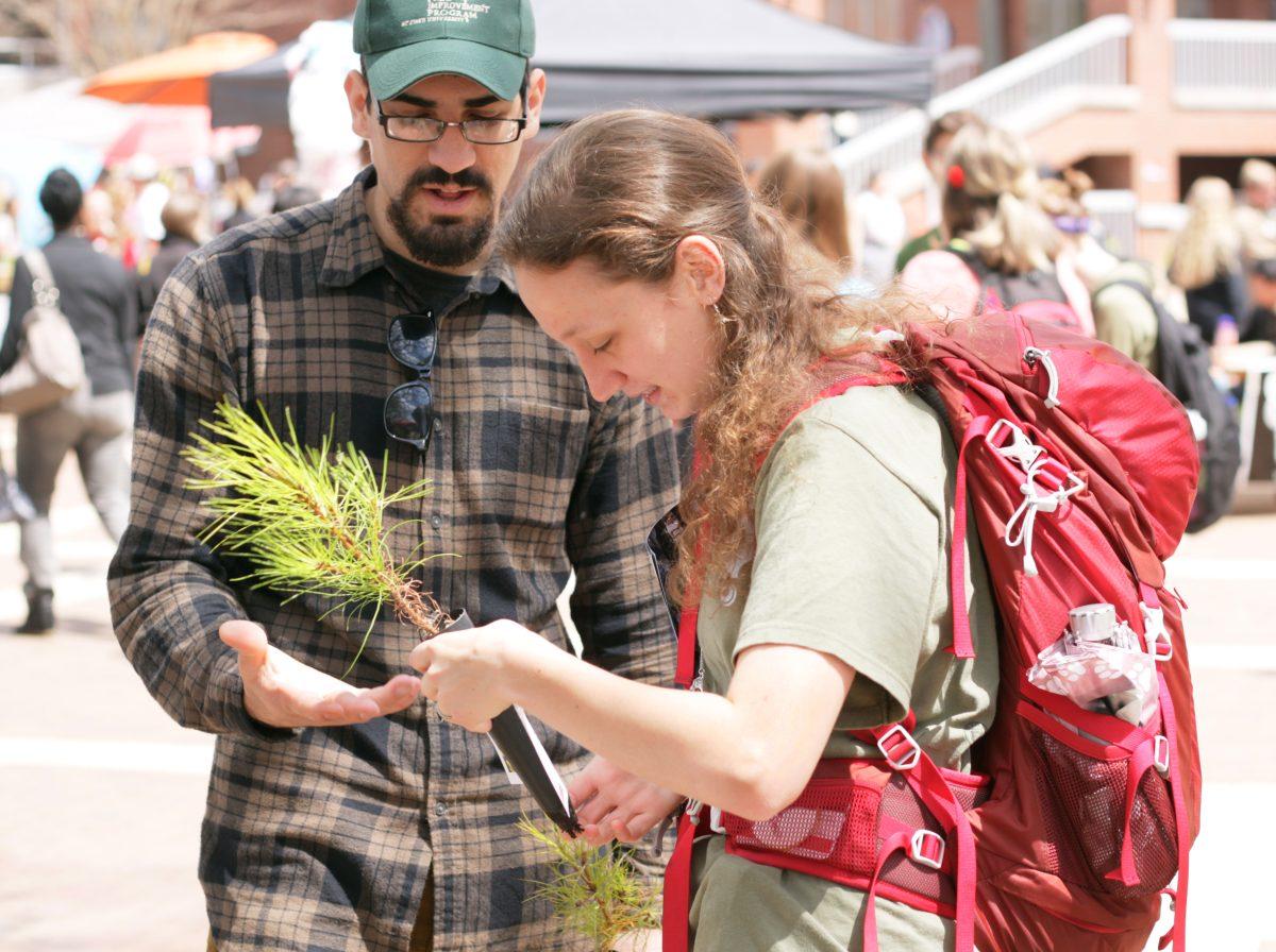 Emily Bruff, a sophomore in biological sciences, talks with Greg Albert, a graduate student in forestry, after receiving a free loblolly sapling at the Tree Improvement Cooperative booth during the Earth Day Fair on Wednesday April 9. The fair brought all kinds of people together in order to raise awareness about sustainability and the N.C. State community.&#160;