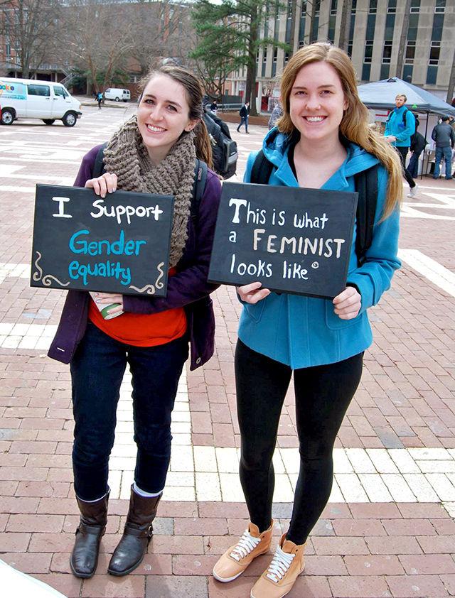 Susanna Helton (left) and Alexa Konzman, seniors in fashion and textile management, hold signs as part of one of SAGE&#8217;s events on the Brickyard.