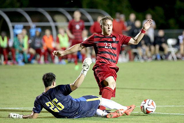 Freshman midfielder Zach Knudson leaps over College of Charleston goalkeeper and shoots the ball for a goal. The Wolfpack took the win against College of Charleston 2-0 on September 16th, 2014. Photo by Nick Faulkner