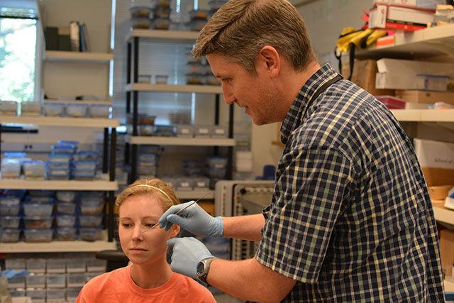 Dan Fergus, an entomologist at NC State, takes a sample from an undergraduate in the mite lab. Research has found that the mites seem to accumulate on the human face with age.