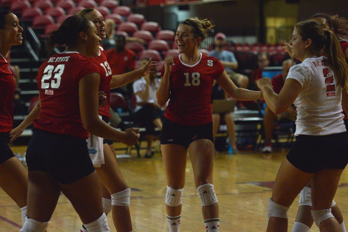 Players from the women's volleyball team embrace each other after the team scored a point while playing Toledo on Saturday, September 6, 2014. The Wolfpack beat the Rocks 3-0 at Reynolds Coliseum. Photo by Kasey Cingel.