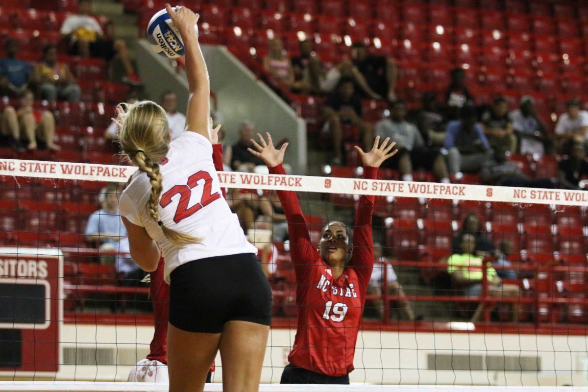 Redshirt freshman outside hitter M.C. Preddy spikes the ball against senior middle blocker Alesha Wilson, Friday, August 22, 2014 during the Red vs. White scrimmage in Reynolds Coliseum. The team divided up after each set into different squads to test various groups of players.