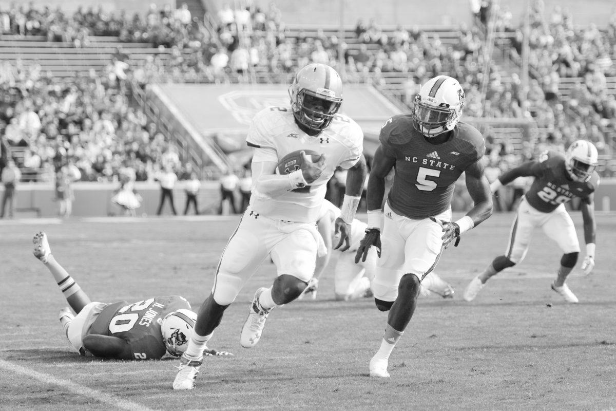 Redshirt junior safety Hakim Jones and senior linebacker Rodman Noel are left in the dust by Boston College quarterback Tyler Murphy early in the first quarter Saturday, Oct. 11, 2014, at Carter-Finley Stadium. Jones and Noel totaled 13 tackles and assists during the game. The Wolfpack tacked on another loss to the season on a score of 14-30, taking their season record to 4-3 and 0-3 in conference play. Photo by Caide Wooten.
